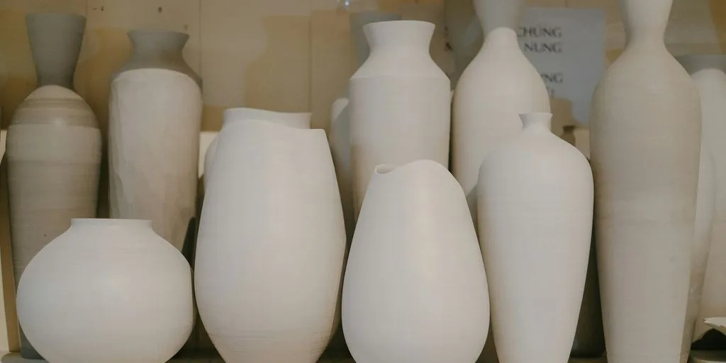 a bunch of white vases sitting on a shelf